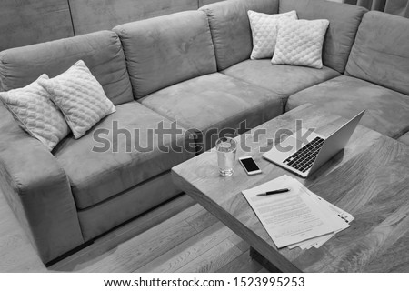 Black and white photo of Laptop and documents on table in apartment