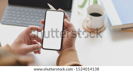 Close-up view of man holding blank screen smartphone while working on his project 