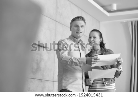 Black and white photo of Couple reading agreement paper while standing in apartment