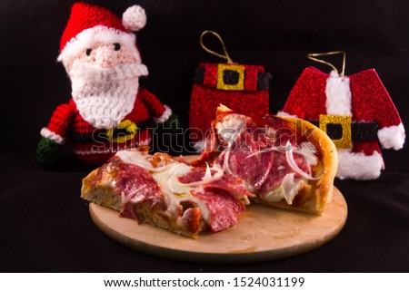 beautiful slice of Italian pizza with the background of Santa Claus and his clothes ideal for Christmas dinner