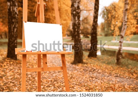 Easel for drawing and empty white sheet of paper in the autumn park. autumn paint concept