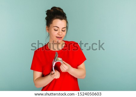 Young woman hold towards a stack of money isolated on blue background - Image