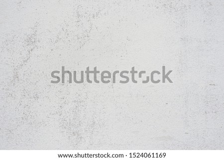 Concrete wall texture with small cracks carelessly painted with white paint