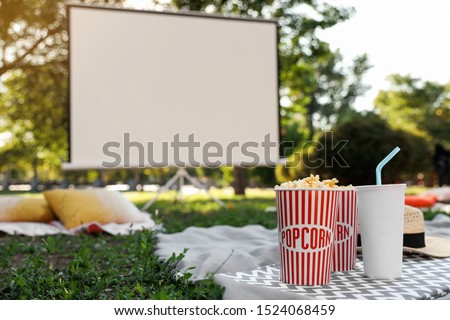 Popcorn and drink on green grass in open air cinema. Space for text