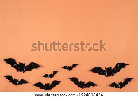 Halloween holiday background with Black paper bats flying over pastel orange background. Halloween and decoration concept.