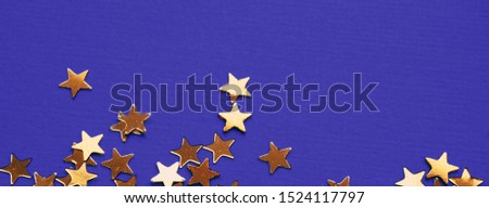 Golden stars glitter on violet background. Festive holiday bright backdrop. Social media banner or header.