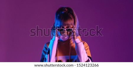 Pretty young 20s fashion teen girl model wear glasses blowing bubble gum looking at camera standing at purple studio background, igen teenager in trendy stylish night glow 80s 90s concept, portrait
 Royalty-Free Stock Photo #1524123266