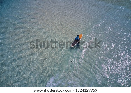 Aerial photography in Maldives, man on the surfboard.