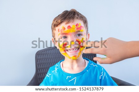 Boy playing with colors using his hands and his face