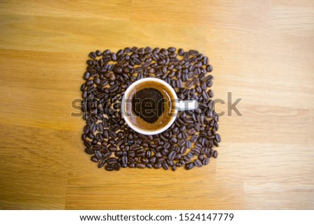 A cup of coffee and coffee beans on the wooden table. Black background. Copy space of your text. Banner.