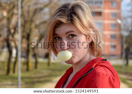 Young blonde woman puffed up a bubble of chewing gum.