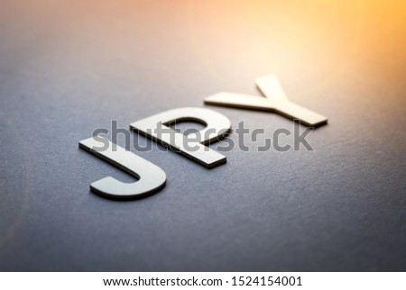 Word JPY written with white solid letters on a board