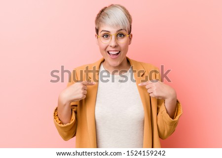 Young caucasian woman wearing a casual business clothes surprised pointing with finger, smiling broadly.