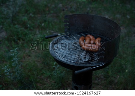 a picture of sausages being barbecued outdoor with green grass as background