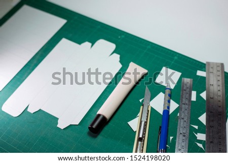 Product or packaging design and development template boxes design artwork on cutting board with tools. Handcraft design template cosmetic box with equipment such as cutter knife, ruler, pencil.