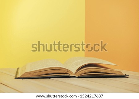 Beautiful book on a wooden table and yellow orange wall background.