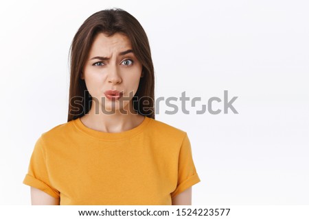 Ouch it probably hurts. Pity good-looking modern brunette woman in yellow t-shirt cringe and grimace as seeing someone got punched in face, folding lips and look uneasy camera, white background Royalty-Free Stock Photo #1524223577