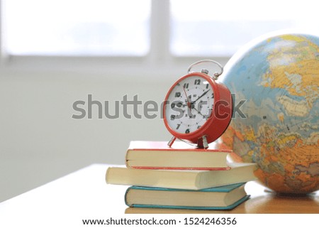 An ancient alarm clock on the pile of books Globe as background selective focus and shallow depth of field