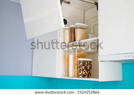 Modern kitchen open kitchen cabinet . Stocked kitchen pantry with food - pasta, buckwheat, rice and sugar . The organization and storage in kitchen of a case with grain in plastic containers.
