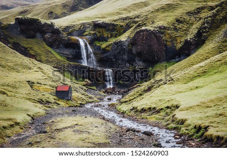 Typical Icelandic scenery. Fresh green hills and waterfall.  Picture of wild area. Iceland.