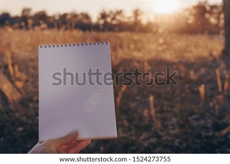 Blank greeting card. Vintage old  rustic background. Wedding invitation card paper on sunshine background. Hand holding empty card in a park in sunny rays. Copy space.Mockup. 