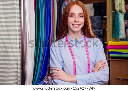 redhair ginger woman choosing color textile in tailor shop for new cloth sewing.she determines the colors that best suit an individual based.