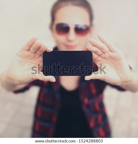 Close up female hands holding black blank screen phone, woman taking selfie picture by phone in city