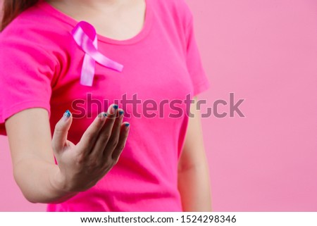 Breast cancer awareness month, Woman in pink t-shirt with satin pink ribbon on her chest, supporting symbol of breast cancer awareness campaign in October.