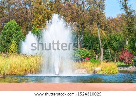  Fragment of the park in Mezhyhiria near Kiev, fountains on the lake. Scenery of nature with sunlight.