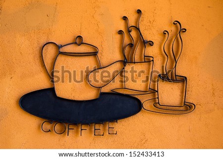 coffee wrought iron on orange wall - sign of coffee shop/cafe
