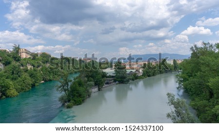 Dark and light river merge into a single one. View from above. The concept of the unity of opposites. In this incredible photo, we see the confluence of the Rhone and Arve rivers in Geneva, Switzerlan