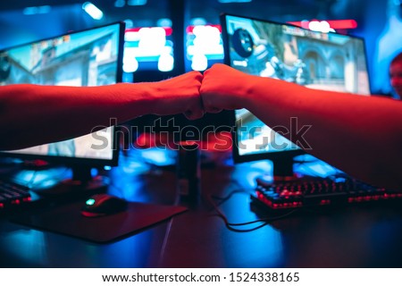 Professional gamer greeting and support team fists hands online game in neon color blur background. Soft focus, back view. Royalty-Free Stock Photo #1524338165