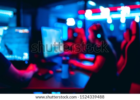 Blurred background professional team gamer stream playing tournaments online games computer with headphones, red and blue