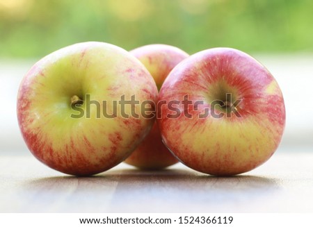 Red apples on wooden table in the garden. Apple is good for health because it is rich with vitamin c and other minerals that help keep body balanced. Selective focused picture of Fruits on table.
