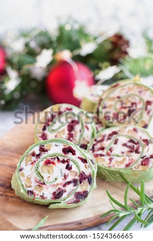 Fresh homemade cranberry pinwheels made with cream cheese, dried cranberries, walnuts, goats cheese and rosemary ready for the holidays. Selective focus with blurred background.