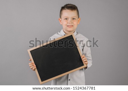 Portrait of a little boy holding a Board on a gray background