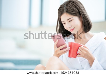 asian beauty woman use smartphone when sitting on lounge chair to relax with coffee or tea