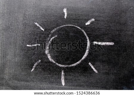 White color chalk hand drawing in sun with ray shape on blackboard background