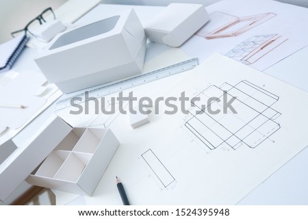 Development design drawing packaging. Desktop of a creative person making cardboard boxes. Royalty-Free Stock Photo #1524395948