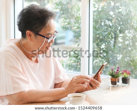 Active and happy senior woman  sitting in the coffee shop , using mobile phone and smiling happily.