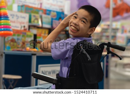 Disabled child on wheelchair trying begged parents to buy a toy for him in Books and toys fair,Special children's lifestyle,Life in the education age of special need kids,Happy disability kid concept.