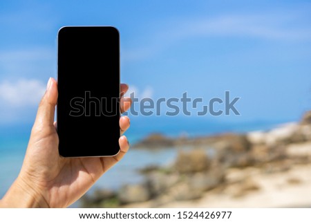 Hand holding smartphone on beach with copy space. Tourism business concept, Shopping concept, Comunication concept