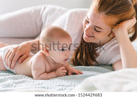 Mom hugs with her newborn baby in bed. Four month old baby. Baby care, tenderness, motherhood