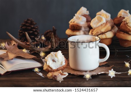 Hot, steaming cup of coffee with cinnamon roll and open book Selective focus on drink with extreme blurred foreground and background. 