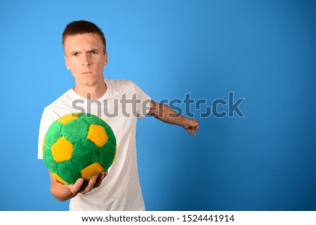 serious football player with a ball shows a free place on a blue background