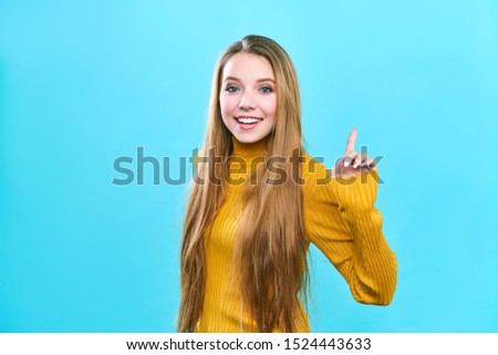 Photo of energetic nice smiling lady isolated on blue background pointing her finger in eureka sign, having great innovative idea
