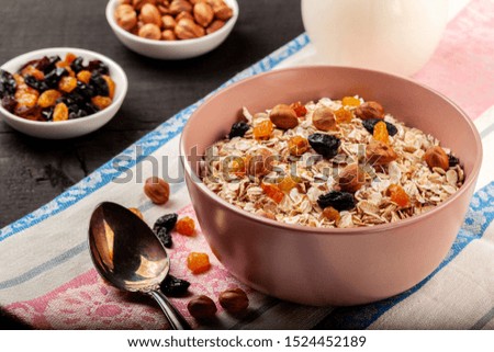 Oatmeal with raisins and nuts in a ceramic bowl on a black wooden table