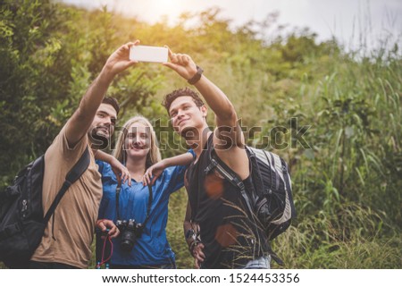 Camping concept - Happy friends having fun with taking pictures  during the holidays. Three cheerful friends in the spring that embrace themselves for a selfie.