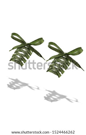 The photo of olive shiny shoelaces with olive tips, hanging in the air on a white background. Shoelaces is casting a shadow. 