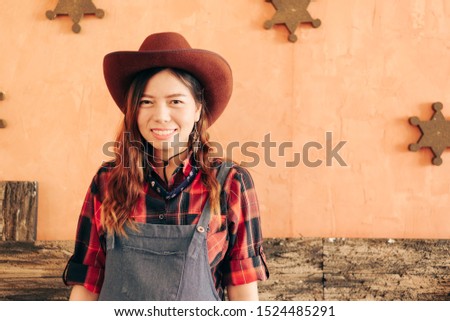 Cowgirl woman smiling happy on american prairie wearing cowboy hat. Asian Caucasian girl in countryside